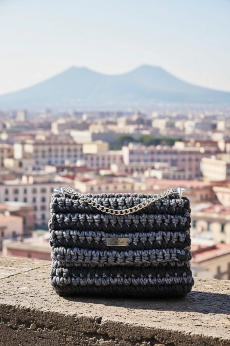 Napoli-Häkeltasche in Dunkelgrau mit silberner Kette, im Hintergrund Neapel und der Vesuv